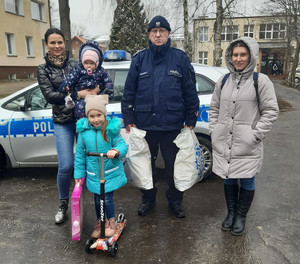 z prawej strony policjantka pośrodku dwójka dzieci, następnie policjant oraz Tatiana, a w tle radiowóz