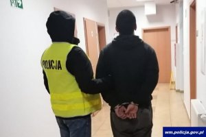 sprawca kradzieży z włamaniem a obok niego policjant