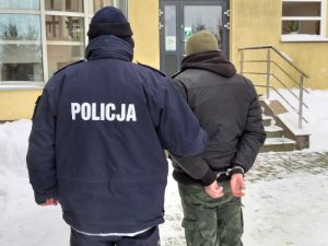 policjant wraz z poszukiwanym na dziedzińcu komendy