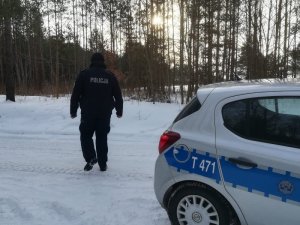 radiowóz, a na dalszym planie dzielnicowy i las