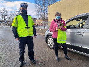 Policjant wraz z kobietą, która wytrzymała kwiata i element odblaskowy