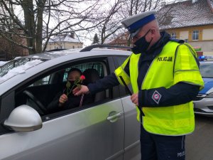 Policjant wręczający kwiaty kierowcy