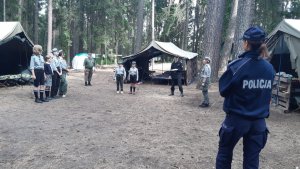 na pierwszym planie policjant zaś na drugim grupa harcerzy