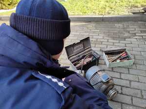 policjant a w tle odzyskane rzeczy typy silnik do piły stołowej oraz klucze