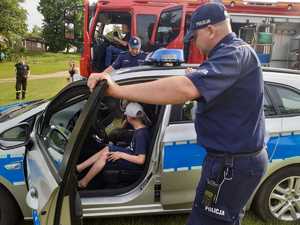 policjant, radiowóz i dzieci za jego kierownicą