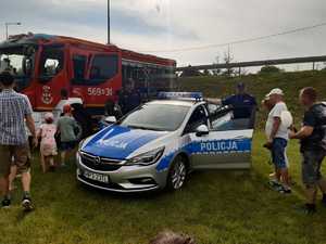 policjant, radiowóz i dzieci za jego kierownicą oraz mieszkańcy Pozezdrza w kolejce do radiowozu