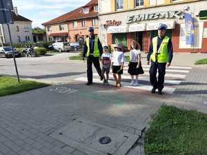 w tle policjanci z uczestnikami ruchu drogowego w trakcie działań Bezpieczna droga do szkoły