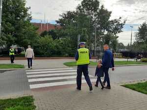 w tle policjanci z uczestnikami ruchu drogowego w trakcie działań Bezpieczna droga do szkoły