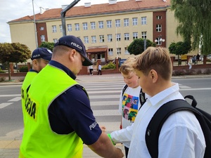 w tle policjanci z uczestnikami ruchu drogowego w trakcie działań Bezpieczna droga do szkoły