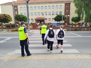 w tle policjanci z uczestnikami ruchu drogowego w trakcie działań Bezpieczna droga do szkoły