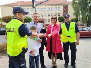 w tle policjanci z uczestnikami ruchu drogowego w trakcie działań Bezpieczna droga do szkoły