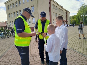 w tle policjanci z uczestnikami ruchu drogowego w trakcie działań Bezpieczna droga do szkoły