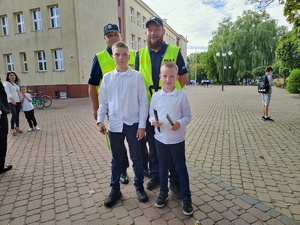 w tle policjanci z uczestnikami ruchu drogowego w trakcie działań Bezpieczna droga do szkoły