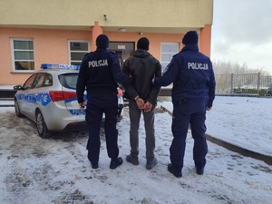 z prawej i lewej strony policjant a po środku zatrzymany
