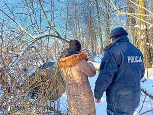 policjant z kobietą stoją odwróceni plecami przy namiocie osoby bezdomnej w lesie