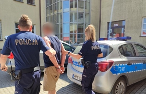 Policjanci prowadzą osobę zatrzymaną